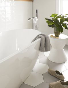 a white bath tub sitting next to a potted plant