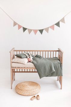 a small wooden bench with pillows and blankets on it next to a rug that is underneath a bunting banner