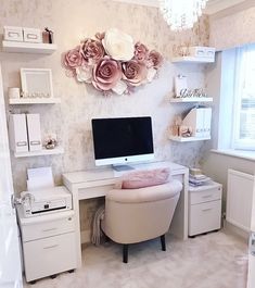 a desk with a computer on top of it in front of a flowered wall