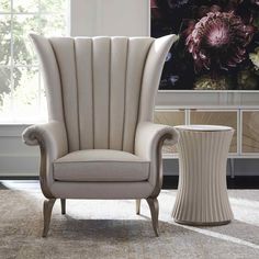 a white chair sitting next to a table on top of a carpeted floor in front of a window