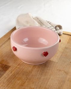 a pink bowl sitting on top of a wooden cutting board next to a pair of gloves