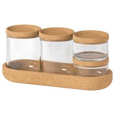 three glass jars with cork lids on a wooden holder