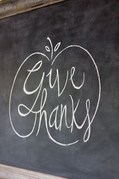 a chalkboard with the words give thanks written in white chalk on it and an apple