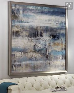 an abstract painting hangs on the wall above a white couch in a living room with blue accents