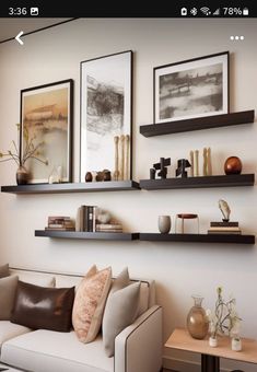 a living room filled with lots of furniture and shelves above the couch, along with pictures on the wall