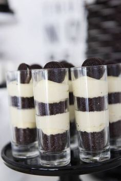 four desserts are arranged on a small black cake platter, with oreo cookies and cream in the middle