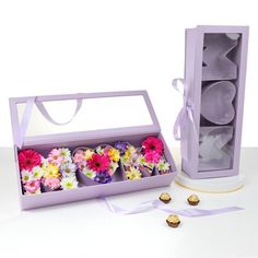 a purple box filled with cupcakes and flowers