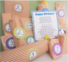 a birthday party with orange and white striped paper wrapped in gift bags, including a sign that says happy birthday