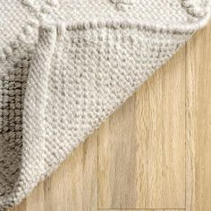 a white rug on top of a wooden floor next to a wood flooring board