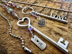 several key chains with charms attached to them on a wooden surface, including one that says love and the other saying i love