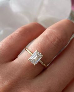 a woman's hand with a diamond ring on top of her finger and an engagement band