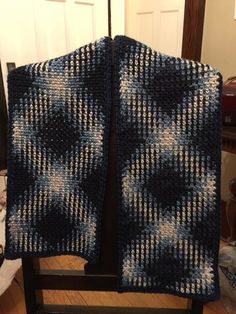 a blue and white blanket sitting on top of a chair next to a door with a black frame