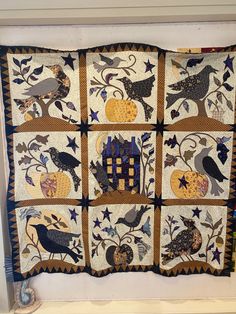 a quilted wall hanging with birds and pumpkins