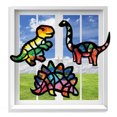 the window is decorated with three colorful dinosaurs in front of a grassy field and blue sky