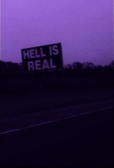 a street sign that says hell is real in front of a purple hued sky