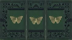 two moths are sitting on the back of a green book with black trimmings