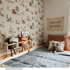 a child's bedroom with dinosaur wallpaper and stuffed animals on the shelf above the bed