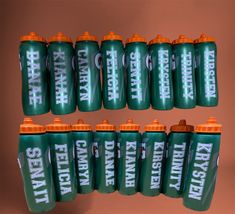 many green and orange sports water bottles are stacked on top of each other in front of a brown background