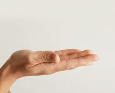 a person's hand holding something in the air with their left thumb extended up