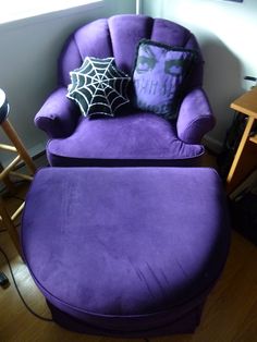 a purple chair with a spider web pillow on top of it, next to a stool