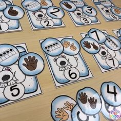 a table topped with lots of blue and white snowman themed counting mats covered in numbers