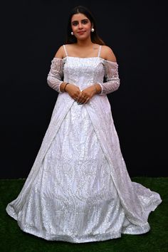 Its a stunning floor-length outfit made from Net fabric in an elegant White color. It features a Off -Shoulder Neck at the front and a Deep Neck at the back. The gown is designed with Cold Shoulder sleeves style. It is embellished with intricate work including Cutdana, Sequins, and Stone work, making it a beautiful choice for special occasions and events. Complete the look by wearing Stone jewelry and bracelet. There might be little color variations in the image and original product due to photo Maxi Length Ball Gown With Sweep Train For Wedding, Wedding Ball Gown With Sweep Train In Maxi Length, Formal Floor-length Gown With Detachable Train, Fitted Sequin Gown For Debutante Ball, Floor-length Gown With Intricate Embroidery And Fitted Bodice, Intricate Embroidery Gown For Debutante Ball, Embroidered Gown With Fitted Bodice For Reception, Embroidered Gown With Fitted Bodice For Debutante Ball, Embroidered Floor-length Gown For Reception