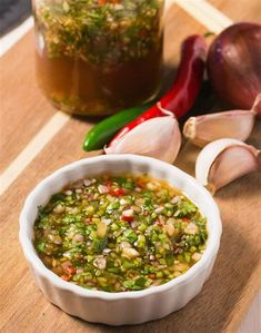 a bowl of salsa next to some garlic and red peppers