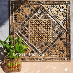 a potted plant sitting on top of a wooden table next to a decorative wall hanging