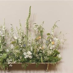 an arrangement of wildflowers and grasses on a shelf