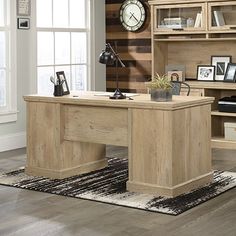 a wooden desk sitting on top of a hard wood floor next to a book shelf