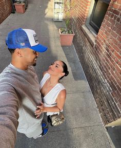 a man and woman standing next to each other on a sidewalk in front of a brick building