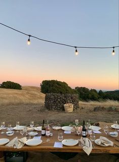 an outdoor dining table set with plates and wine glasses