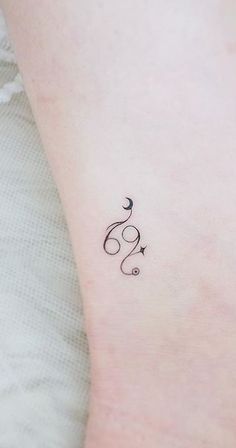 a small tattoo on the ankle of a woman's left leg, with an arrow and stars