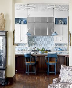 a kitchen with blue chairs and white cupboards in it's center island area