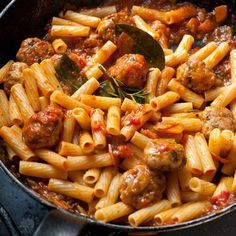 a skillet filled with pasta and meatballs on top of an oven burner