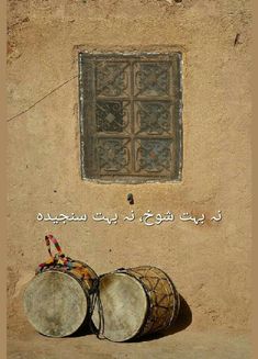 two wooden drums sitting in front of a wall with an arabic writing on the side