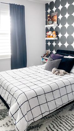 a black and white bedroom with polka dots on the wall behind the bed, along with an area rug