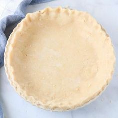 an uncooked pie sitting on top of a table next to a blue towel