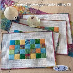 three quilted placemats on a table with a teapot and saucer