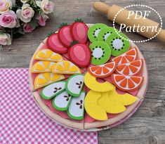 a plate filled with cut up fruit on top of a table next to flowers and a rolling pin