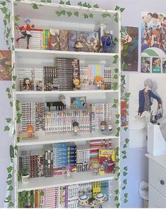 a book shelf filled with lots of books next to a white dresser and wall mural