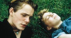 two young men laying in the grass next to each other