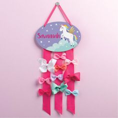 a pink wall hanging with bows and a unicorn on it's back that says savannah