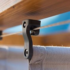 a close up of a metal hook attached to a wooden board with fabric on it