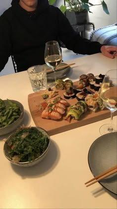 a man sitting at a table with food and wine