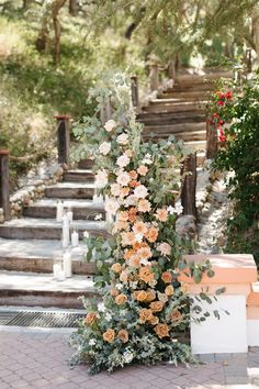 an outdoor wedding ceremony with flowers and greenery on the steps leading up to the aisle