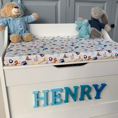 two stuffed animals sitting on top of a white toy crib with the word henry written in blue