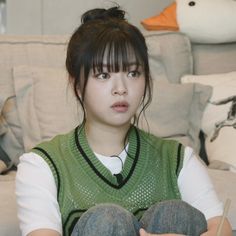 a young woman sitting on top of a couch holding a pair of chopsticks