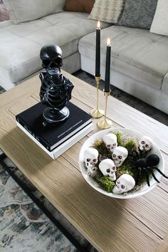 a coffee table with skulls in a bowl and two candles on the end tables next to it