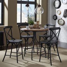 a dining room table and chairs with clocks on the wall behind them in front of a window